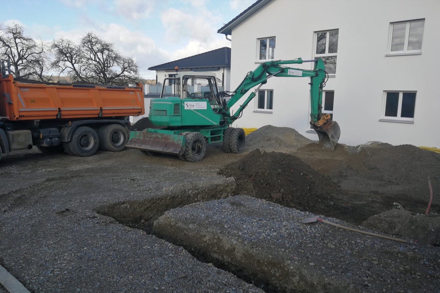Bagger neben einem Kipper auf einer großen Baustellenfläche