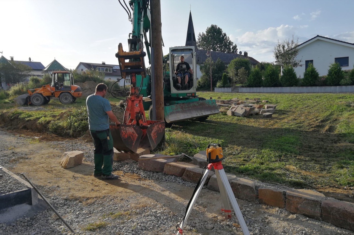 Zwei Personen messen mit einem Nivelliergerät die Höhen auf der Baustelle ein