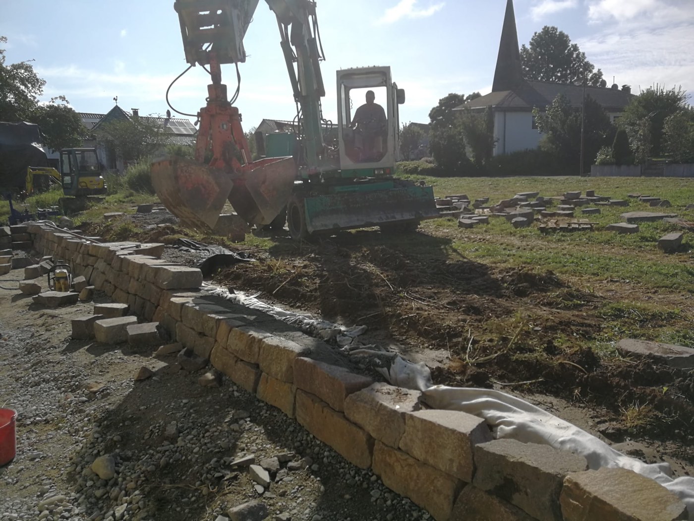 Im Bau befindliche Trockenmauer aus Sandsteinblöcken, gesetzt mit dem Bagger